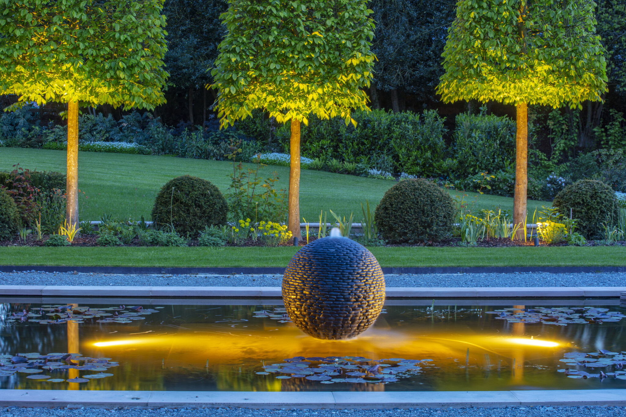 La sphère de jardin Planète Sombre s’allume la nuit.