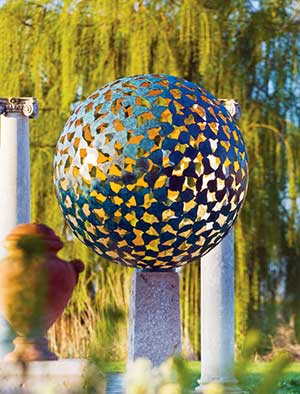 Mantle bronze sphere on a contemporary plinth in a classic garden