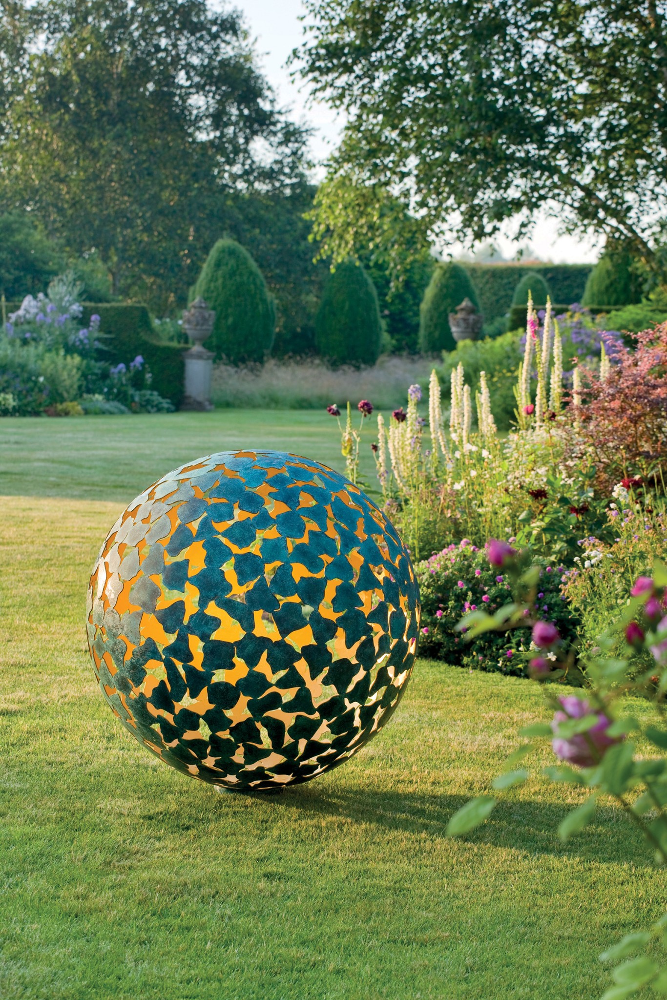 Metallische Gartenskulptur in Form eines Gitters aus bronzenen innen vergoldeten Blütenblättern Gartensphäre aus Stein