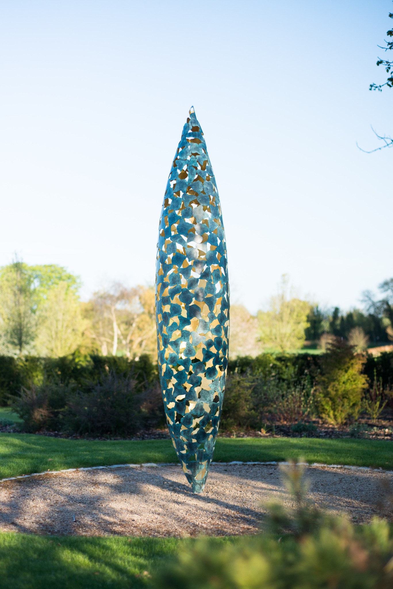 Quill sculpture poised on a lawn with flowers behind