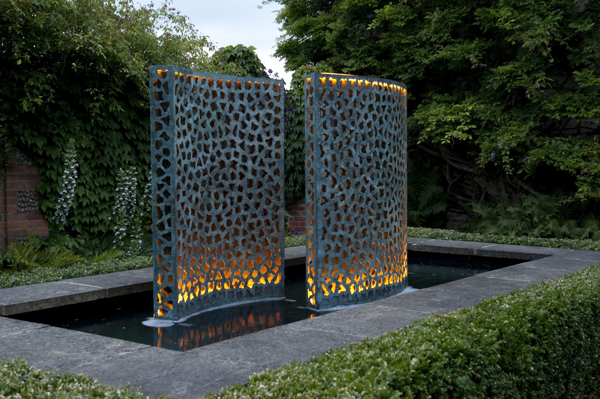 Tres paredes de agua Entramado en bronce con un acabado verde cardenillo iluminadas por la noche