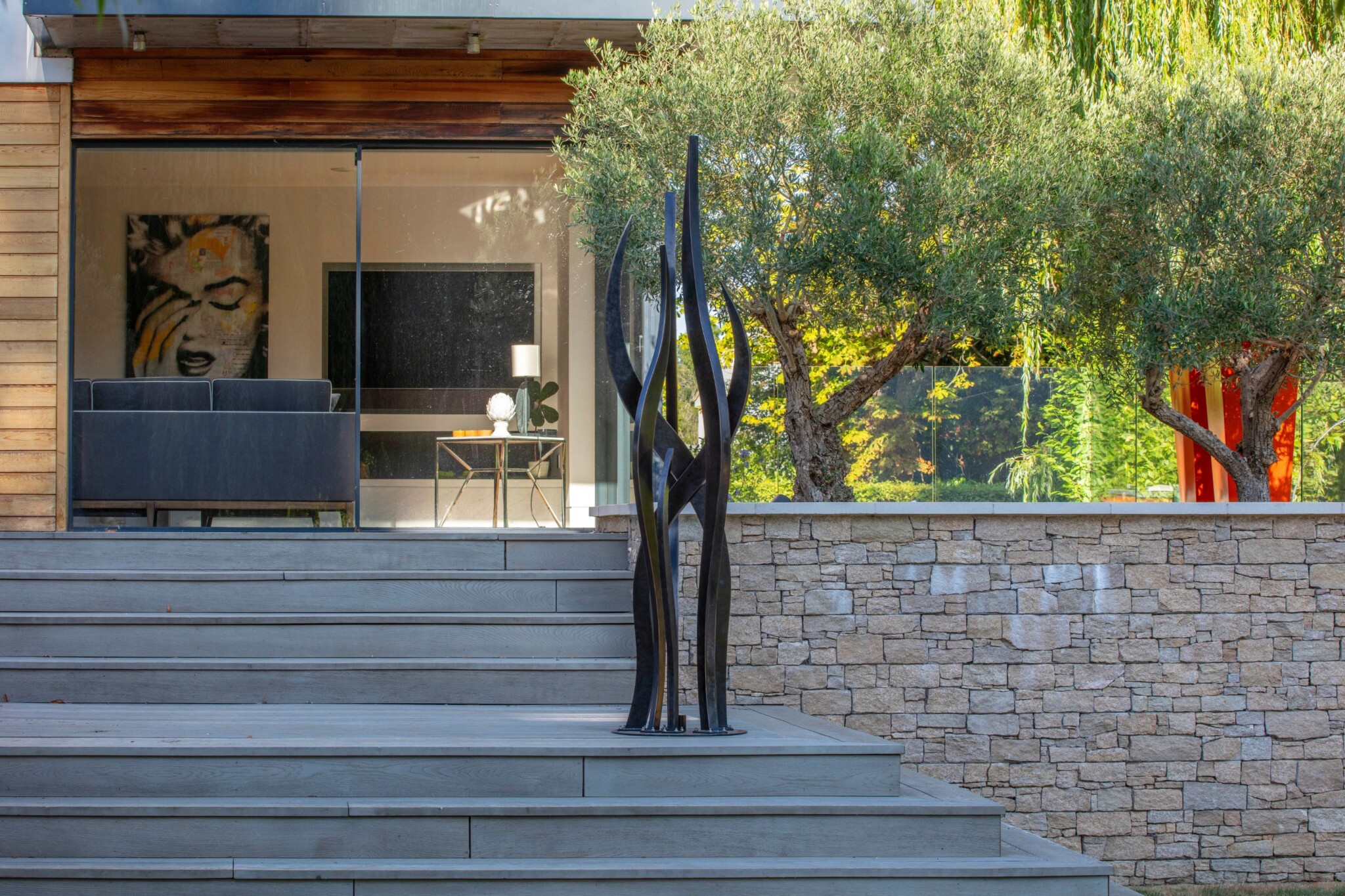 Seaweed like sculpture with a charcoal-black patina marks steps to a modern architectural home.