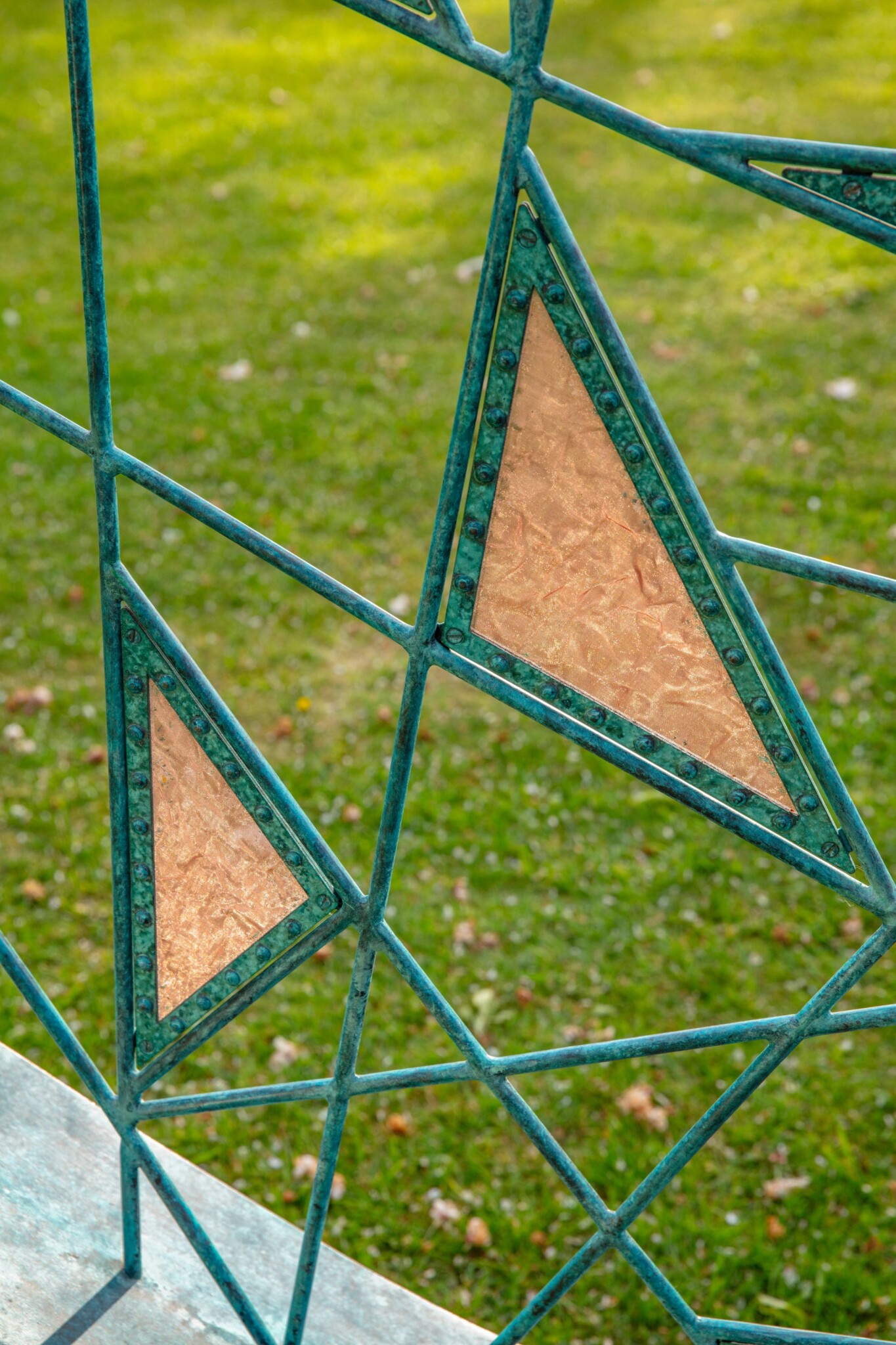 Close up of trangles of tensioned copper mesh held in place with bronze rivets.