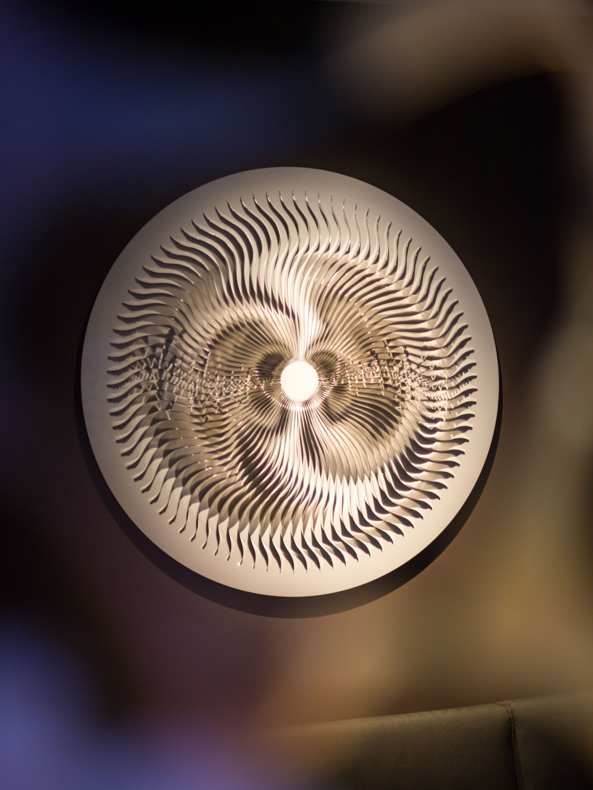 Round stainless-steel metal wall art with fin-shaped details.
