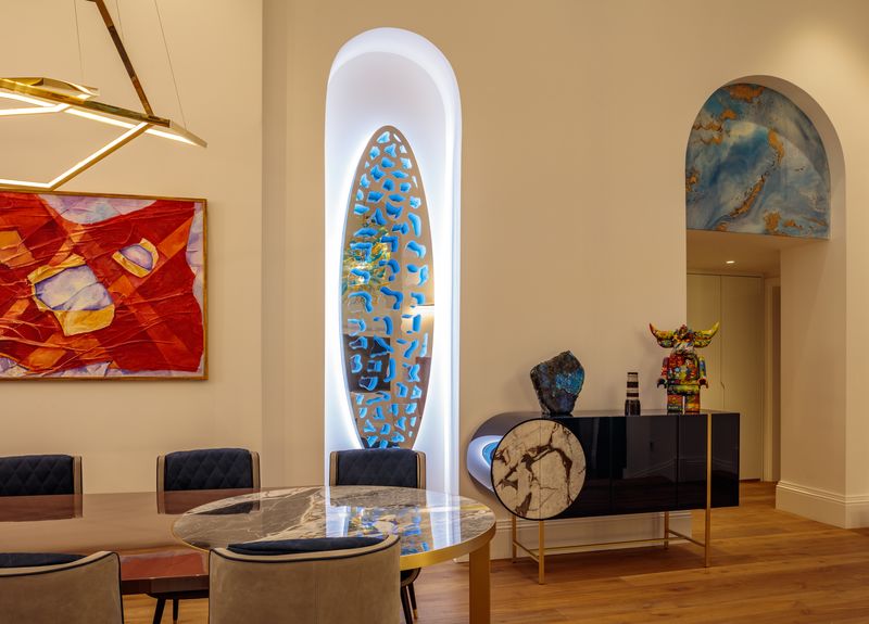 Modern dining room with abstract art, marble table, and blue-lit hallway sculpture ideas in an arched wall recess.