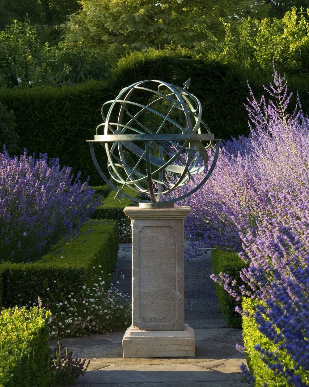An armillary sphere on a stone pedestal, framed by purple blossoms, accents the serene garden setting.