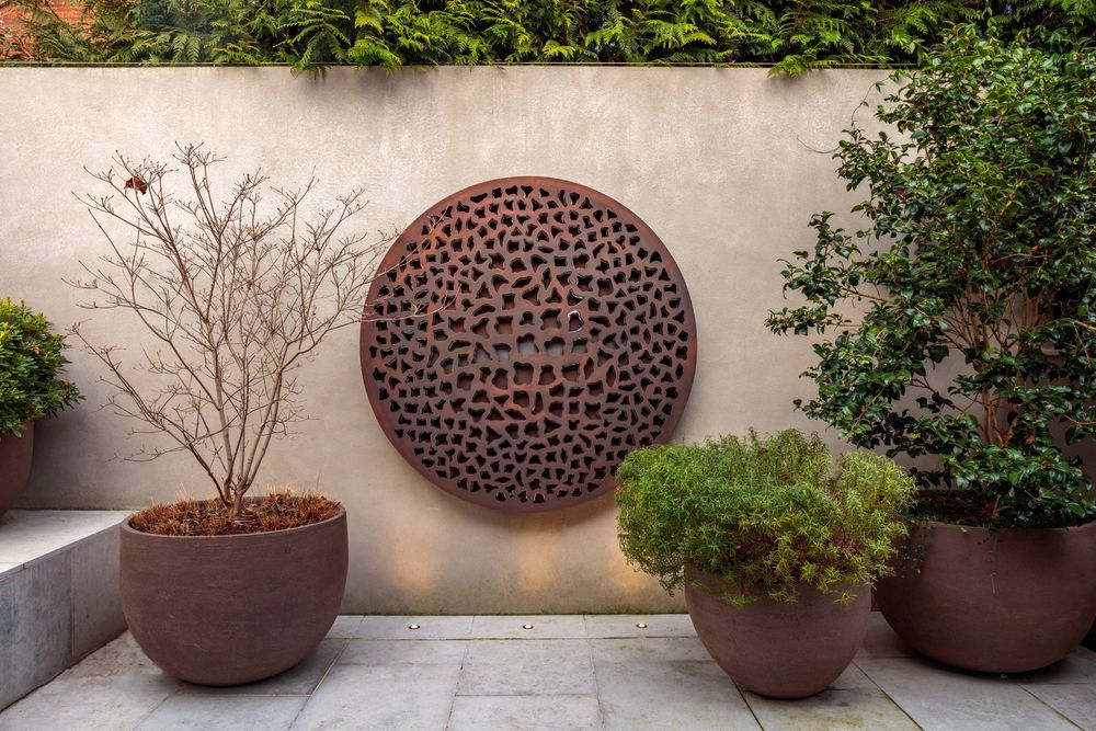 Steel Breeze circular wall sculpture by David Harber features layered metal discs framed by an antique patinated bronze band