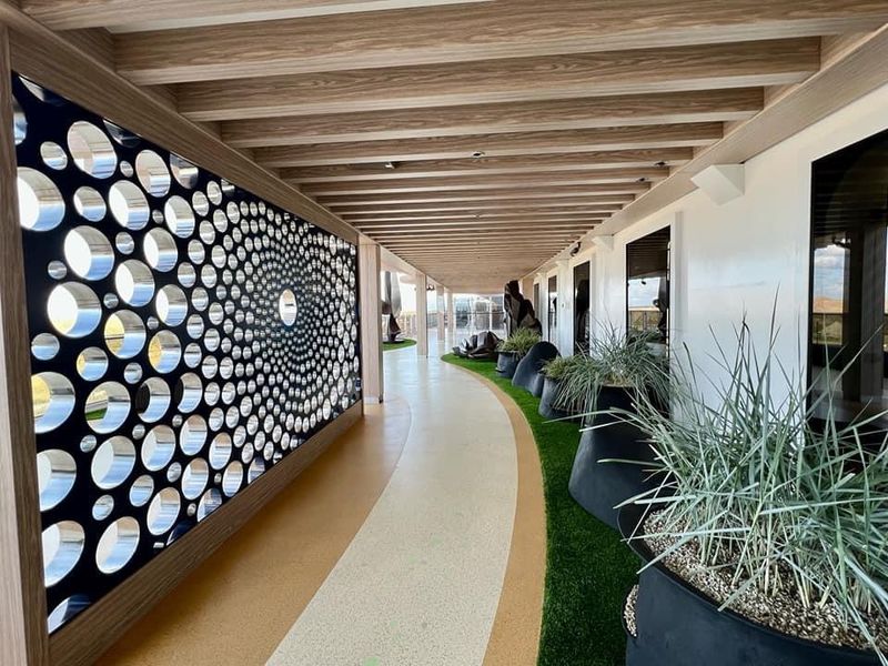 Modern hallway with circular wall art, potted plants, and wooden beams; great for hallway sculpture ideas by large windows.