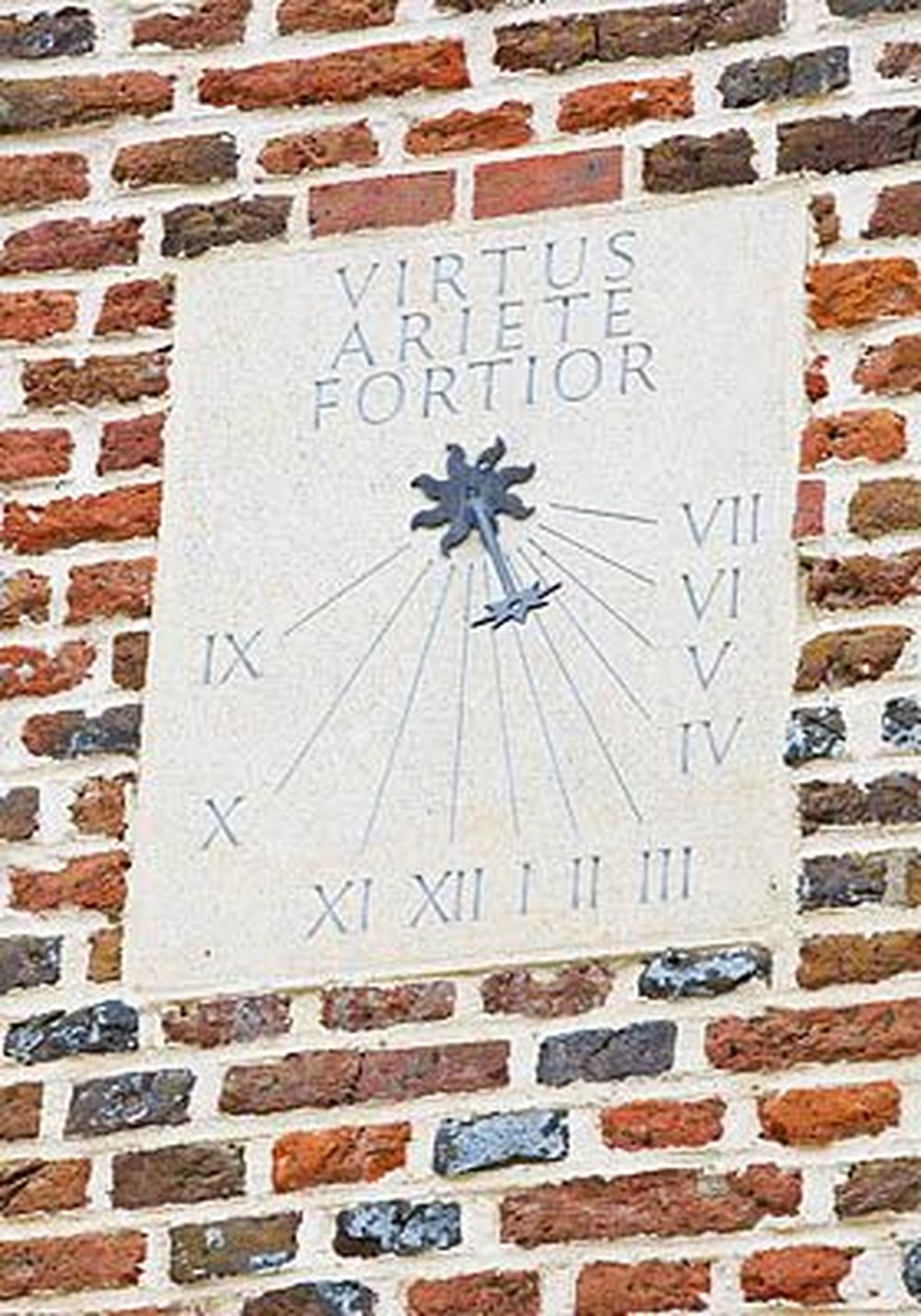 vertical stone sundial by David Harber on a brick wall at Rycote Park, featuring a blue star gnomon