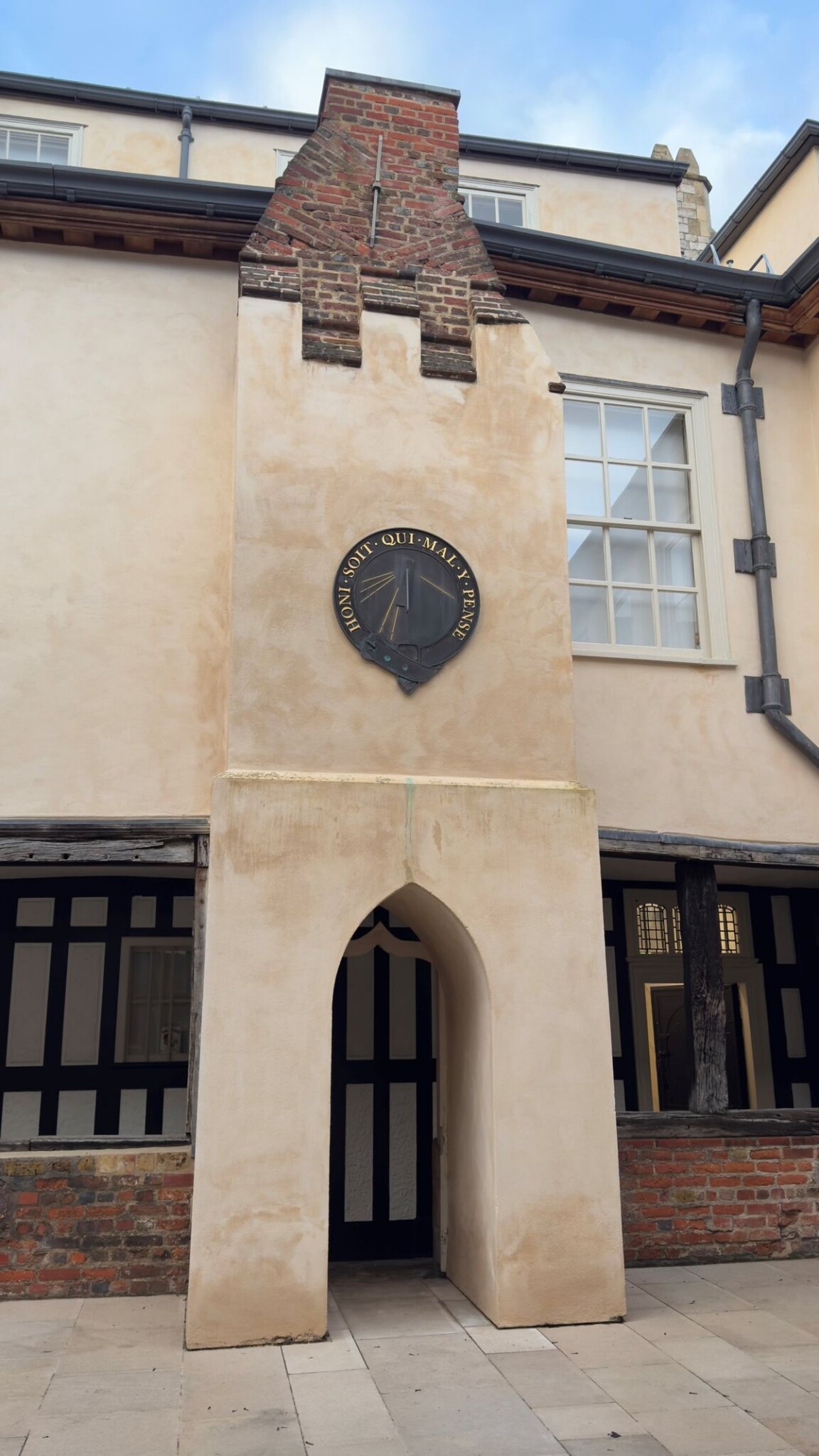 An old building with an arched doorway, a clock above the entrance, and charming garden sundial ideas nearby.